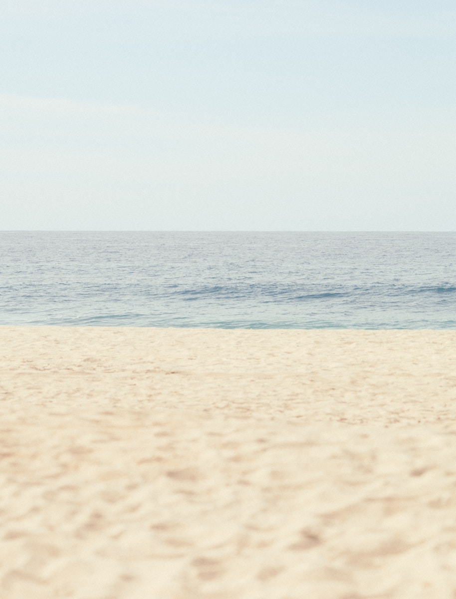 Calm ocean meets a sandy beach under clear sky